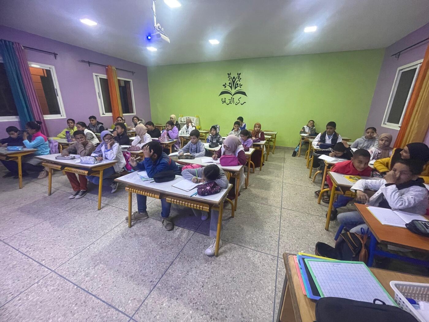 تلاميذ داخل حجرة دراسية بجدران خضراء وبنفسجية أثناء حصة